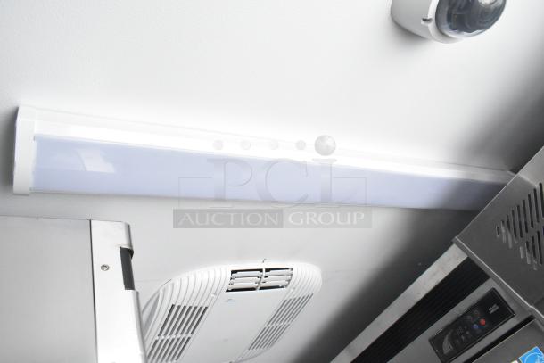 Interior view of a fully outfitted cold food and beverage retail trailer showing a light fixture, air conditioning vent, and control panel.