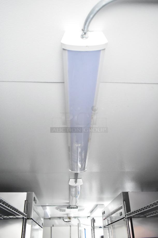 Inside view of cold food and beverage trailer, showing ceiling lighting and stainless steel fixtures. Ideal for commercial use.