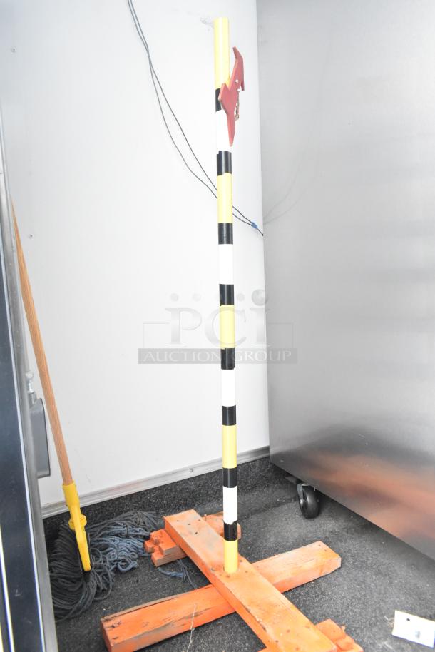 Interior view of a cold food and beverage retail trailer with a striped pole, mop, and stainless steel appliance.