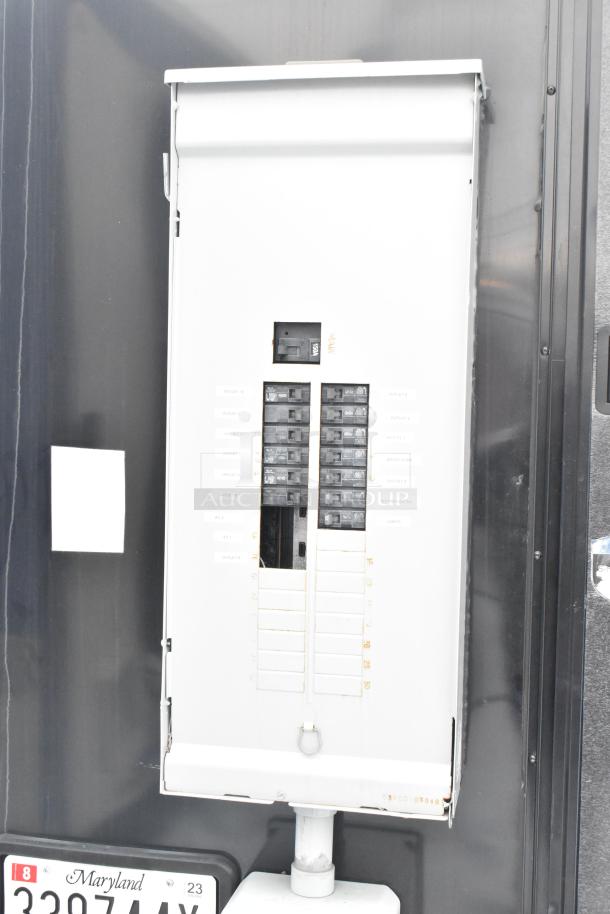 Electrical panel on a cold food and beverage trailer, featuring labeled circuit breakers for various appliances. Maryland license plate visible below.