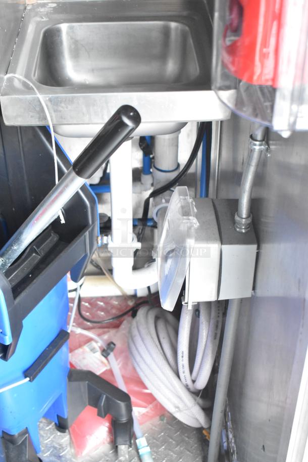 Brand new 2021 Titanium Cargo 28' shell food trailer interior, featuring a stainless steel sink, hoses, and utility setup.