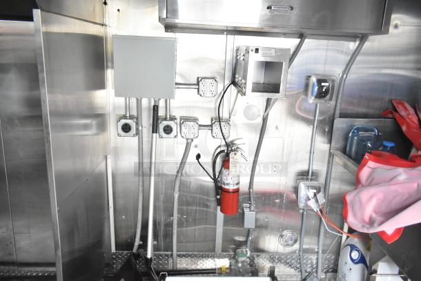 Inside view of a 2021 Titanium Cargo 28' trailer, featuring electrical outlets, grease hood, fire extinguisher, and stainless steel walls.
