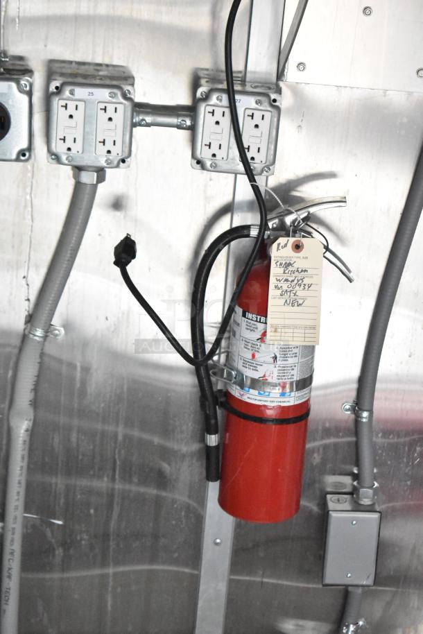 Interior of a 2021 Titanium Cargo 28' food trailer featuring electrical outlets and a fire extinguisher with safety tags.