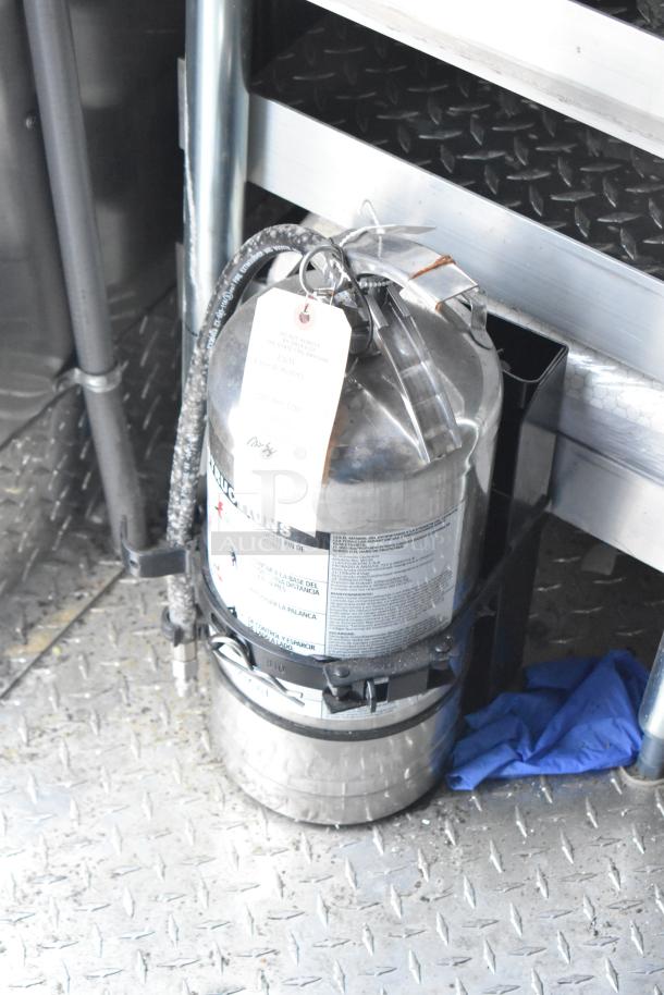 Fire suppression system in a Titanium Cargo 28' Shell Food Trailer with attached hose and labeled instructions.