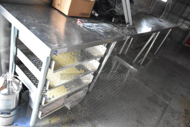 Brand new 28' Titanium Cargo food trailer interior with stainless steel worktops, shelving, and diamond plate flooring.