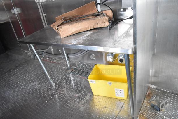 Brand new 2021 Titanium Cargo 28' food trailer interior. Features stainless steel surfaces, utility connections, and yellow bin.