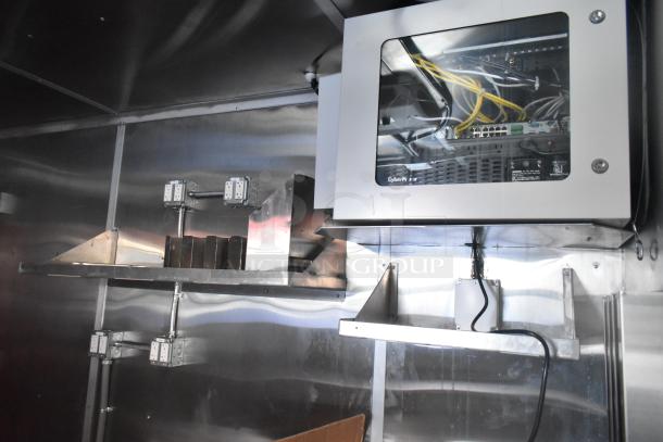 Brand new 28' Titanium Cargo food trailer interior with shelves, grease hood, sinks, and CyberPower security system. Ready for custom buildout.