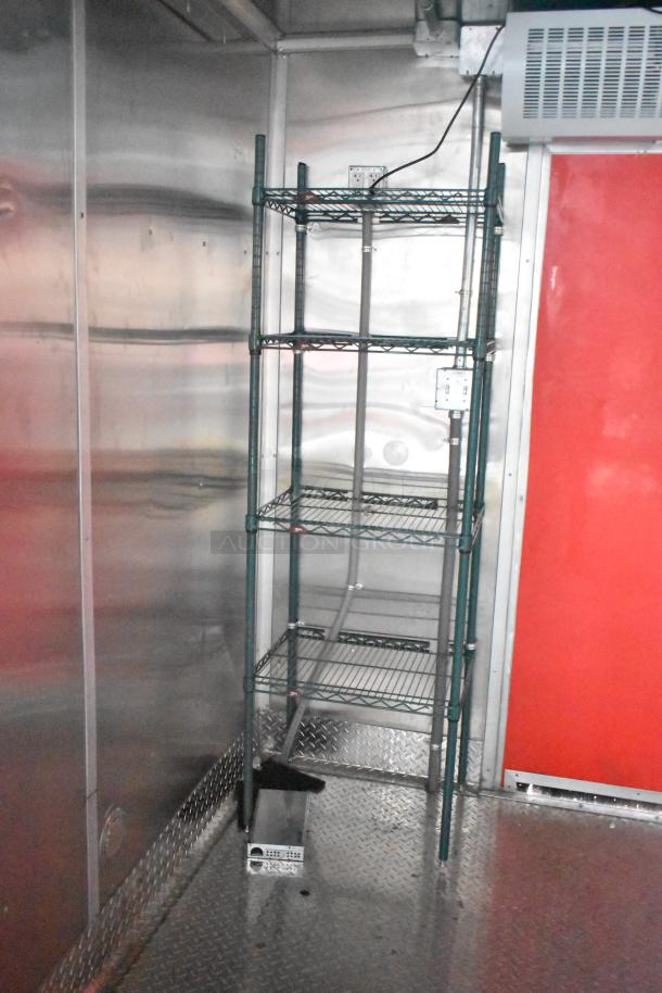 Alt text: Interior of 2021 Titanium Cargo 28' food trailer, featuring metal shelving, diamond plate flooring, and visible sink piping.