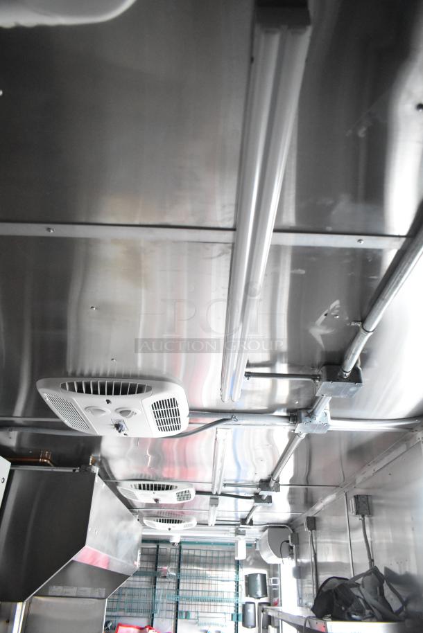 New 28' Titanium Cargo mobile kitchen trailer interior, featuring stainless steel design, grease hood, lighting, and ventilation.