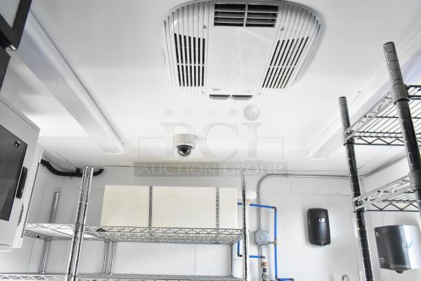 Interior of a 2021 Southern Dimensions mobile food trailer, featuring shelving, ceiling HVAC, and security camera. Clean condition.