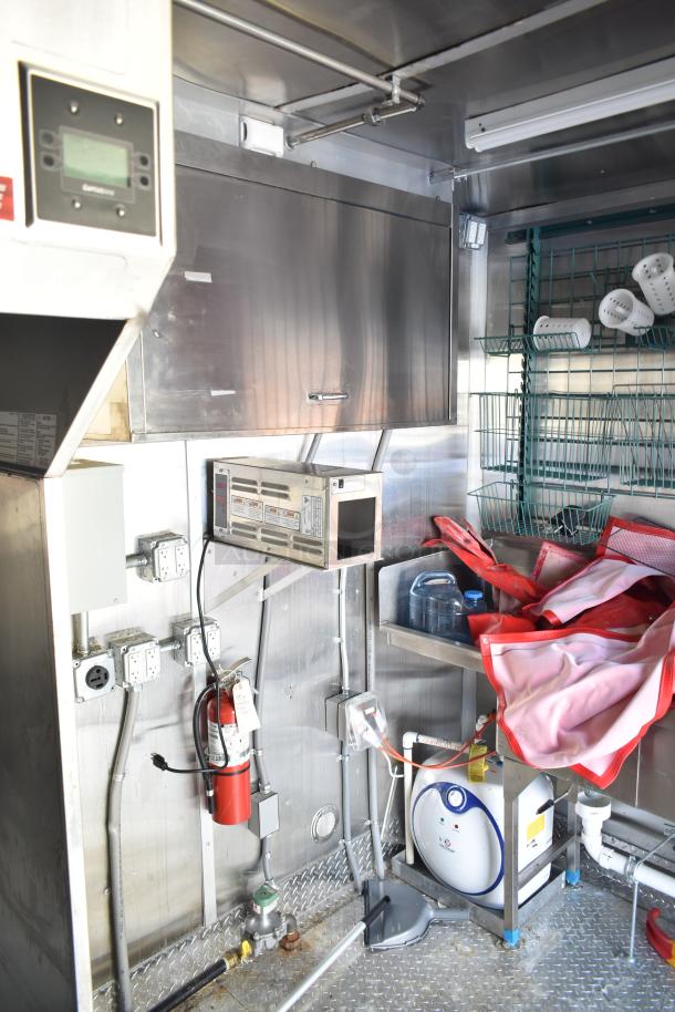 2021 Titanium Cargo 8.5' x 28' mobile kitchen trailer interior. Features grease hood, plumbing, and electrical infrastructure.