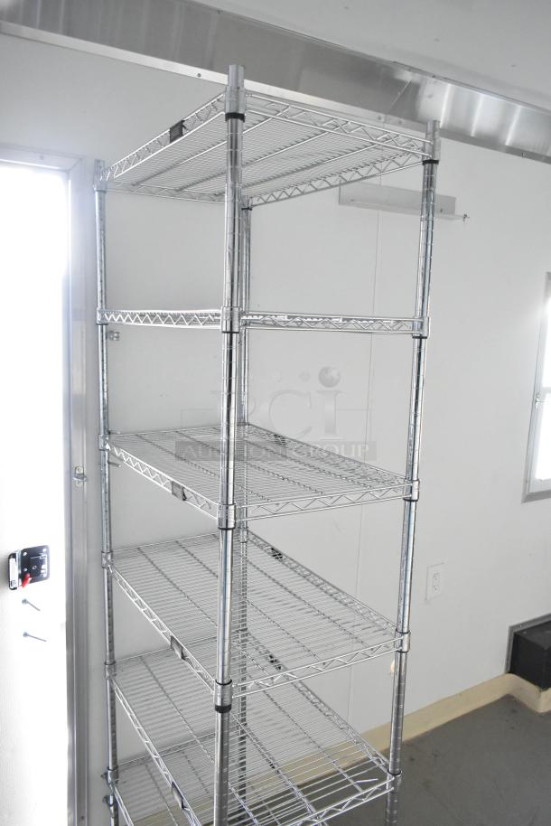 Interior of 2021 Diamond Cargo trailer showing metal Metro shelving, electrical outlet, and door lock detail.