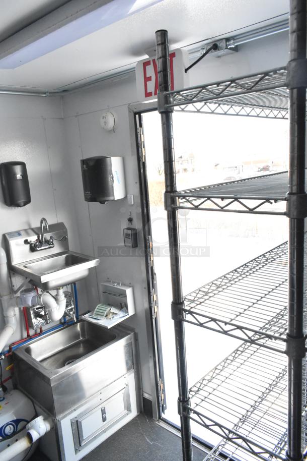 Interior of 2021 Southern Dimensions Mobile Cold Storage Trailer with stainless steel sink, shelving, and exit sign. Near-new condition.