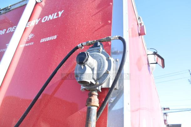 Red mobile kitchen trailer with delivery brand logos, exterior gas hookup shown. Ideal for fast-food operations.