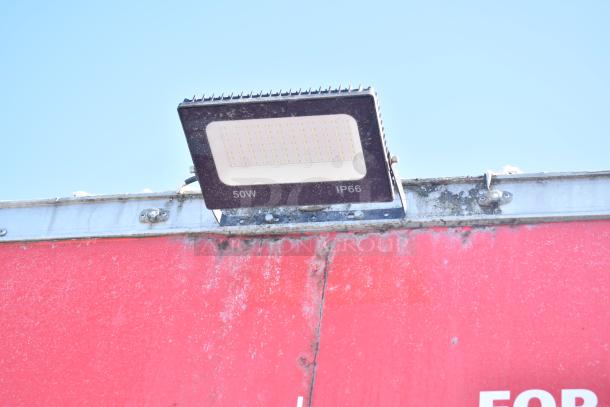 Exterior view of Rock Solid Cargo fast-food trailer showing a 50W IP66 floodlight affixed to the red roof edge.