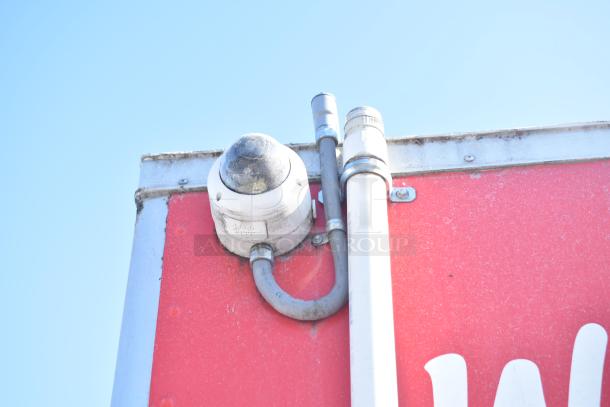 Security camera mounted on a red Rock Solid Cargo fast food trailer, showing outdoor piping and fittings.