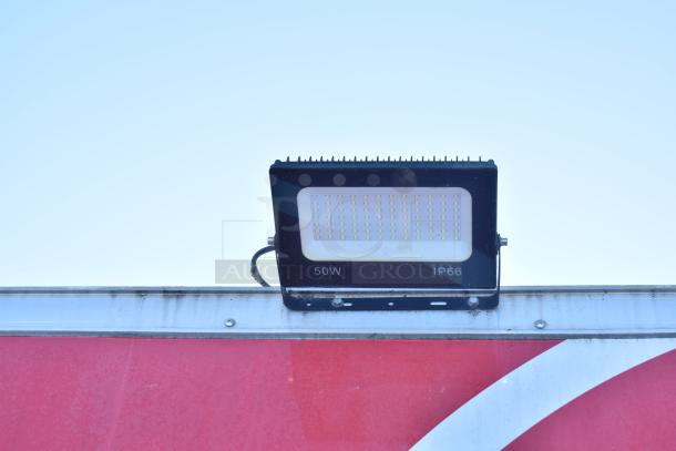 LED floodlight on a fast food trailer, displaying "50W" and "IP66" markings, mounted above red panel.