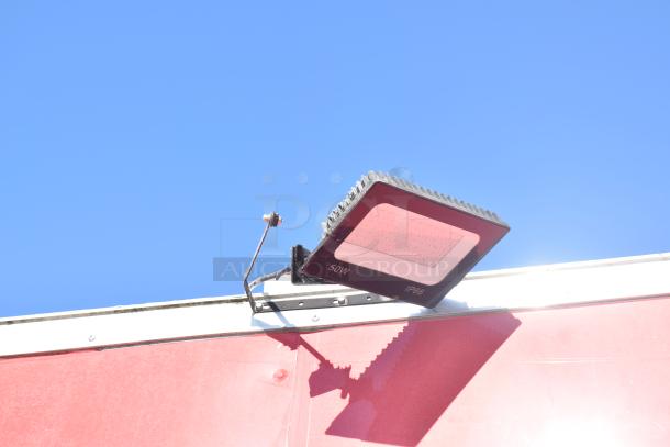 Red mobile kitchen trailer with mounted 50W, IP66-rated floodlight on the exterior. Ideal for high-volume service.