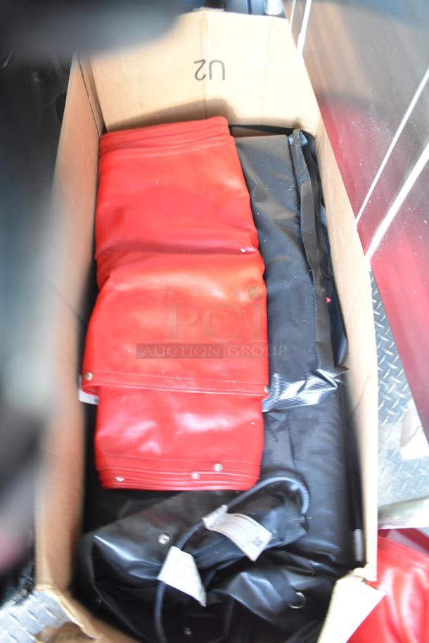 Box with folded red and black fabric covers, possibly for trailer or equipment use, inside Rock Solid Cargo trailer.