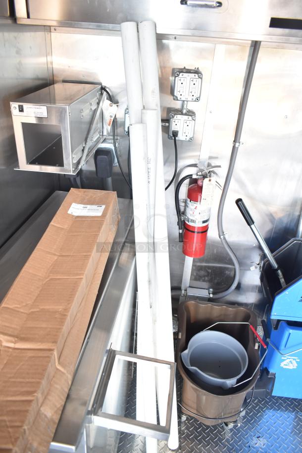 Mobile kitchen interior with commercial-grade system, inc. grease hood, outlets, fire extinguisher, and storage space.