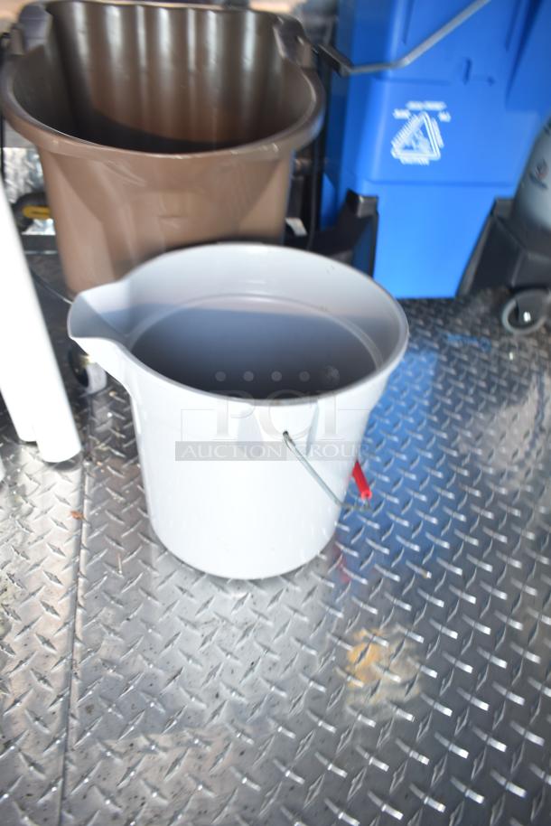 Interior view of a mobile kitchen trailer showing metal flooring, a white bucket, and a brown bin.