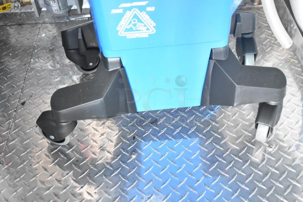Blue mop bucket on diamond plate flooring within a Rock Solid Cargo mobile kitchen trailer. Caution label visible.