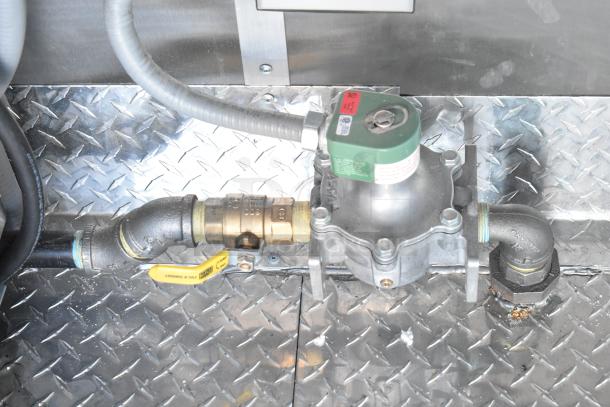 Gas line and valve system on metal flooring of Rock Solid Cargo fast food trailer, showing commercial-grade connections.