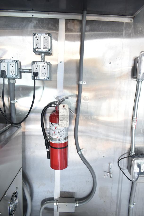 Interior of a Rock Solid Cargo fast-food trailer showing electrical outlets and a mounted fire extinguisher.