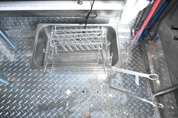 Interior of a Rock Solid Cargo fast-food trailer showing a stainless steel sink with racks on a diamond plate metal floor.