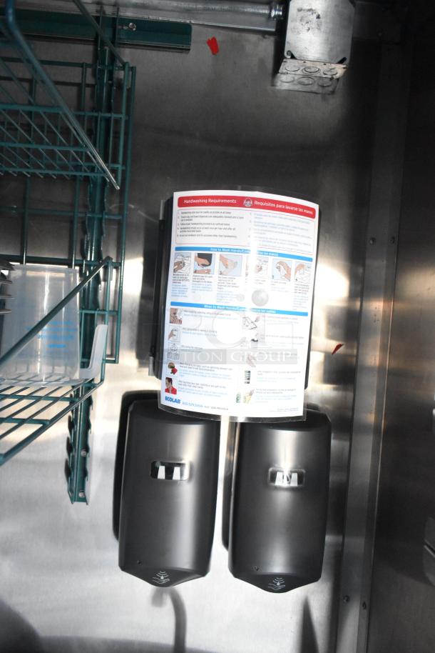 Interior view of a Rock Solid Cargo mobile kitchen with Ecolab soap dispensers and handwashing instructions visible on a metal wall.