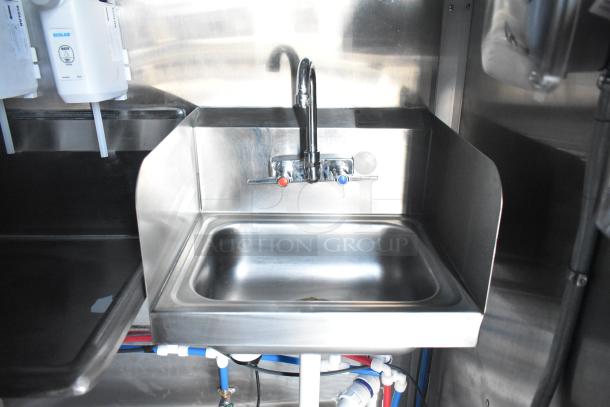 Stainless steel sink in Rock Solid Cargo mobile kitchen trailer, featuring dual temperature controls and Ecolab sanitizer dispensers.