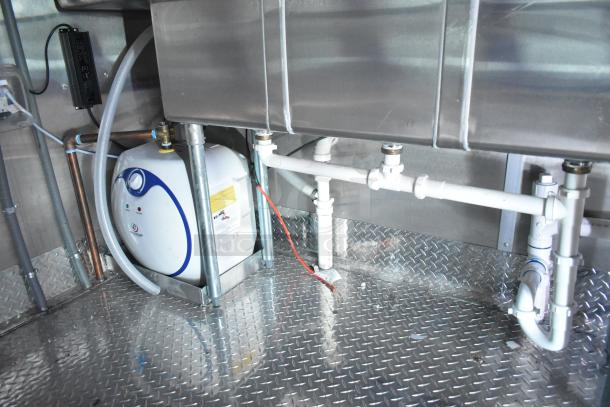 Interior of a 2022 Rock Solid Cargo fast food trailer, showing installed plumbing and stainless steel wall panels.