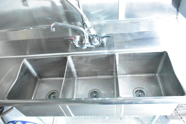 Stainless steel three-compartment sink with faucet inside Rock Solid Cargo mobile kitchen trailer.
