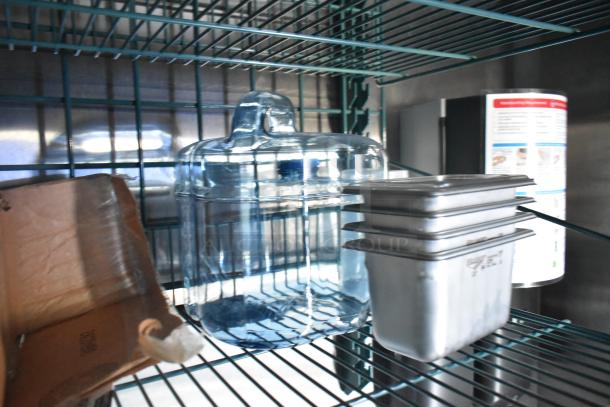 Rock Solid Cargo trailer interior showing shelving with stainless steel pans, a large glass jar, and cardboard box.