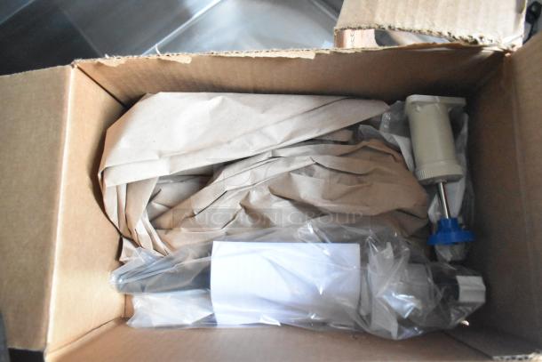Cardboard box containing wrapped components of a fast food trailer, including a pump system part.