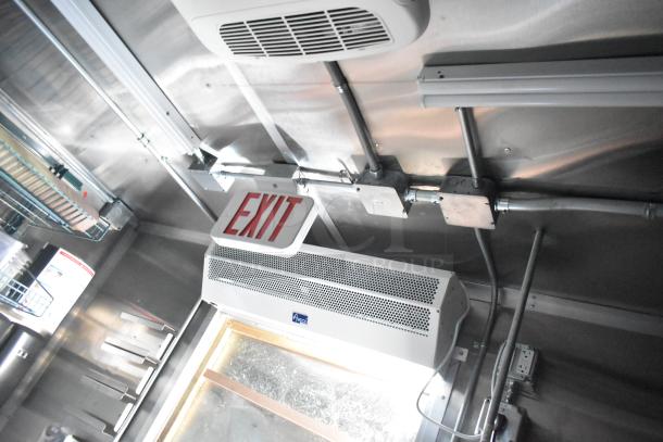 Interior view of a Rock Solid Cargo fast food trailer showing an EXIT sign, HVAC vent, and wiring. Stainless steel surfaces are visible.