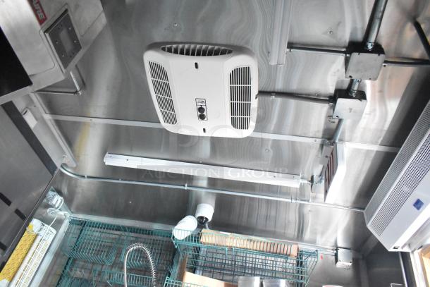 Interior of a 2022 Rock Solid Cargo fast food trailer, featuring stainless steel walls, electrical fixtures, and a ceiling vent.