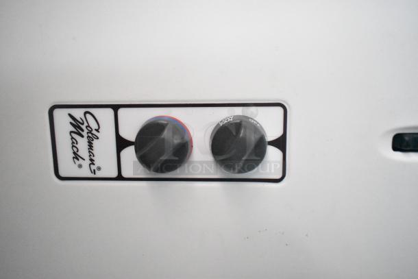 Coleman-Mach control panel with two black knobs labeled for temperature and fan settings on a mobile kitchen appliance.