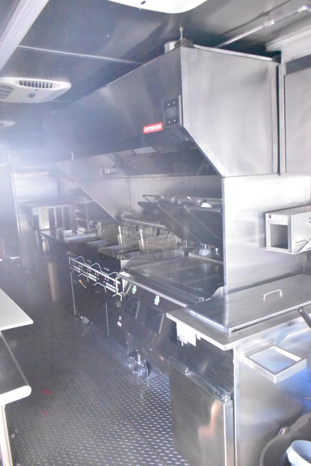 Rock Solid Cargo fast-food trailer kitchen with CaptiveAire grease hood, fryers, and stainless steel fixtures, new condition.