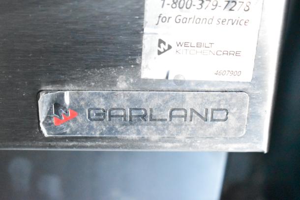 "Garland" label on commercial kitchen equipment, includes Welbilt KitchenCare contact info for service.