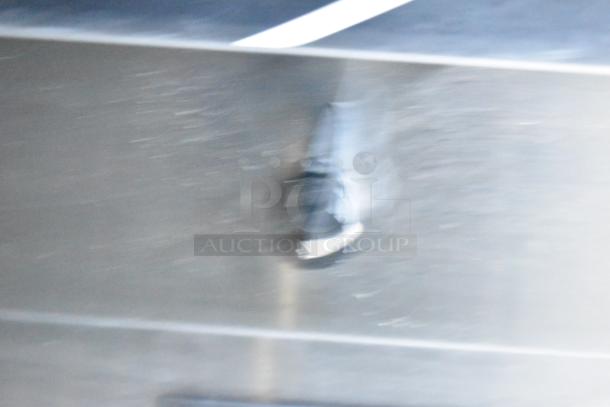 Blurry image showing a gray surface with faint motion blur, possibly capturing part of a moving object or person.