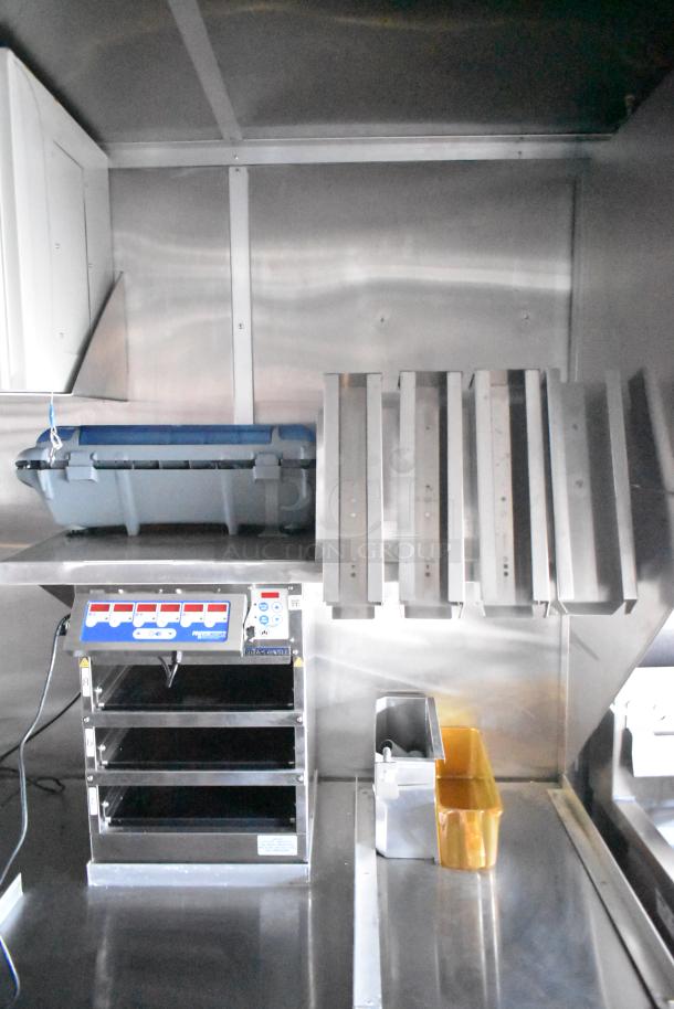 Rock Solid Cargo fast food trailer interior showing food prep equipment, metal shelves, and control panel, all in new condition.