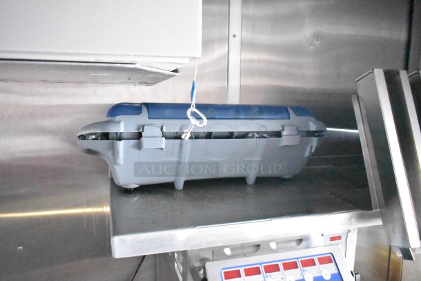 Rock Solid Cargo mobile kitchen interior, featuring a grey and blue appliance, stainless surfaces, and control panel.