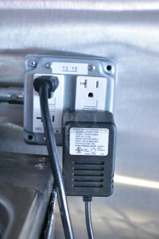 Electrical outlet with two sockets and a plug, labeled "13 15," in a Rock Solid Cargo fast-food trailer kitchen.