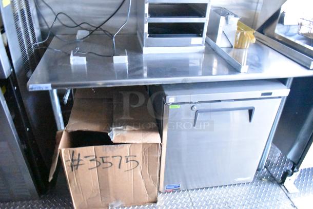Rock Solid Cargo fast-food trailer kitchen interior, stainless steel counter, commercial fridge, and labeled box #3575 visible.