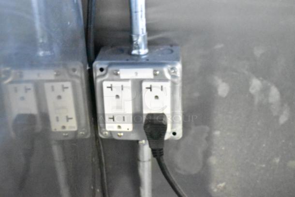 Electrical outlet with two sockets in a Rock Solid Cargo fast food trailer, showing a power cable plugged in.