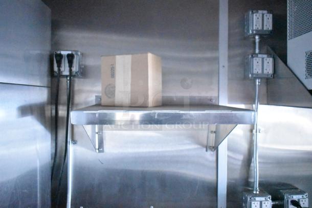 Rock Solid Cargo mobile kitchen interior with stainless steel shelves, electrical outlets, and a cardboard box.