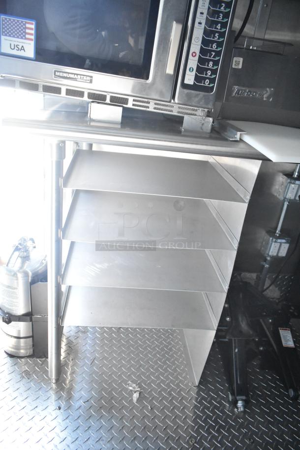 Rock Solid Cargo fast food trailer interior, featuring a Menumaster microwave, fire extinguisher, and stainless steel shelves.