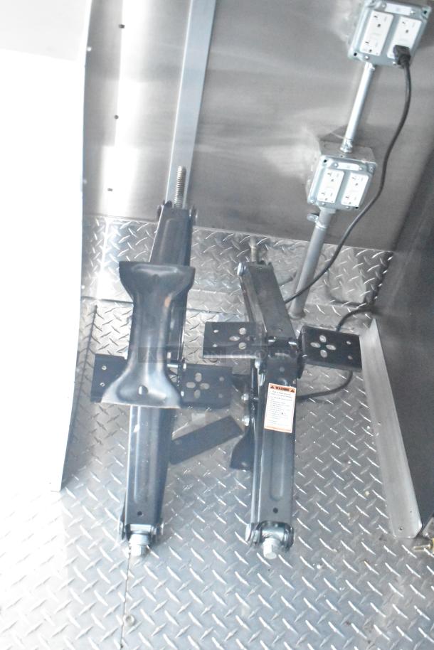 Interior of Rock Solid Cargo fast-food trailer, featuring electrical outlets and jacks on diamond plate flooring, new condition.