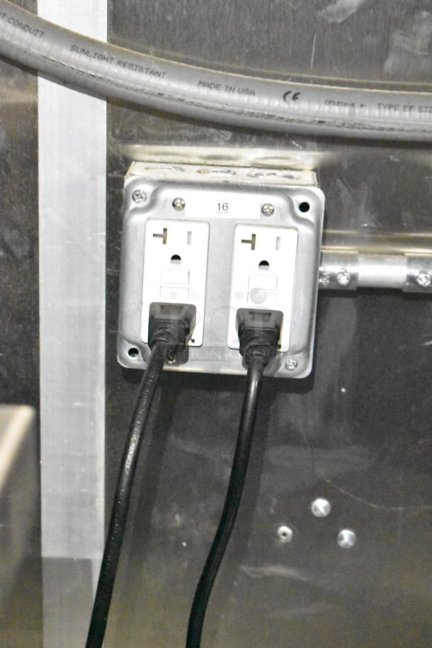 Electrical outlet with two sockets, labeled "16," inside Rock Solid Cargo fast food trailer. Plugged-in power cords visible.